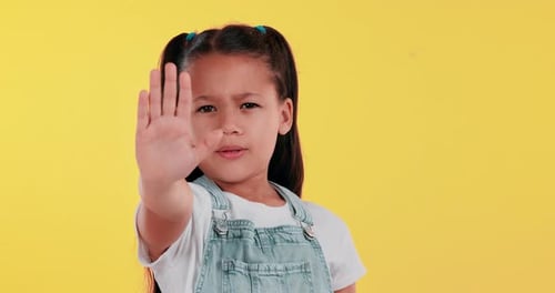 Young girl, face and stop in hand on studio background for warning, protest and wrong action