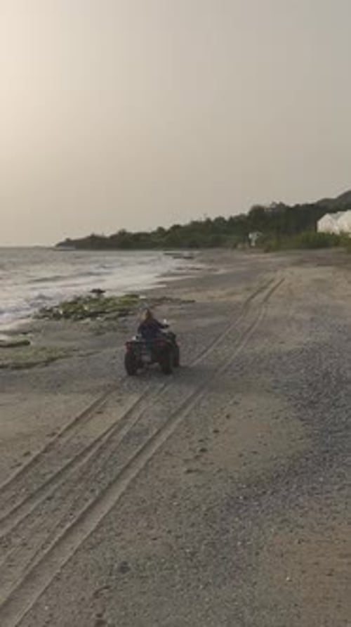 Vertical Video Glamorous Model Exploring the Mediterranean Coast on a Quad Bike at Sunset