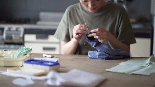 Woman Hand-Sewing Fabric at Kitchen Table