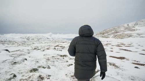 Tracking Shot Of A Man Walking Alone At A Snowy Mountain