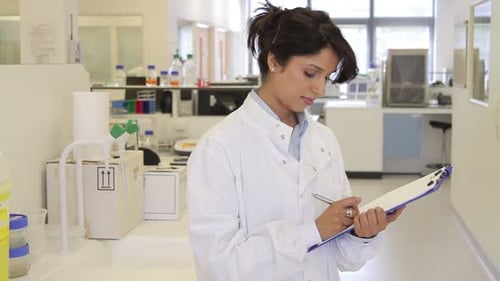 Woman in Lab Coat Writing on Clipboard
