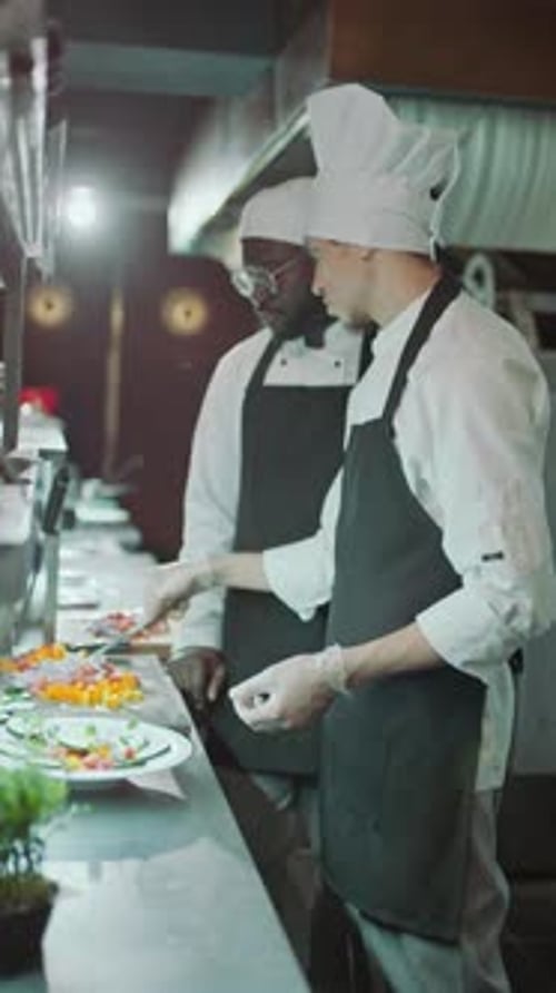 Koch serviert Essen auf dem Teller und unterrichtet Auszubildende in der Küche eines Restaurants