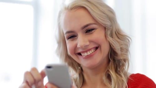 Blonde woman smiles while using a mobile phone
