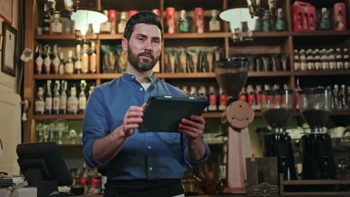 Male Cafe Owner Working on Digital Tablet While Controlling Service Quality