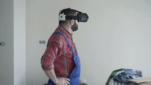 Jeune homme faisant l'expérience de la conception de maison en réalité virtuelle avec des lunettes VR à l'intérieur