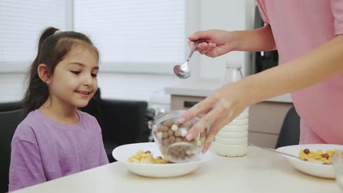 Girl Having Breakfast with Mother at Kitchen Table