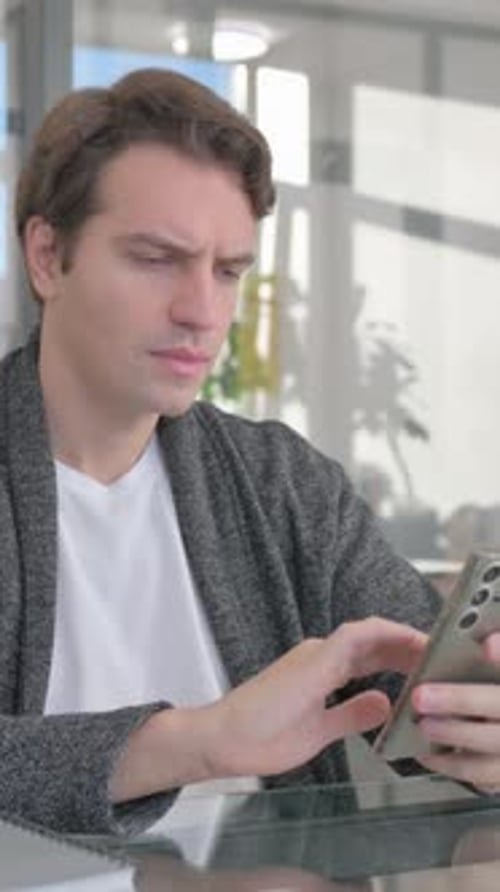 Young Man Browsing Internet on Phone in Office, vertical video