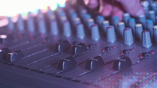 Hand Settings Volume Level Controls on Mixing Console Faders Neon Light CloseUp