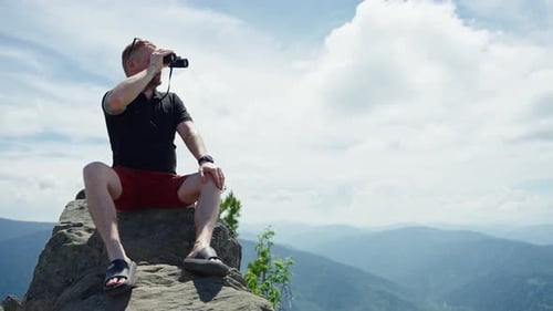 Man Looking at the Horizon Using Binoculars in the Mountain