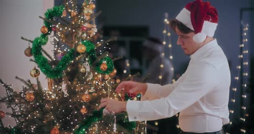 Young Man Decorating Christmas Tree at Home