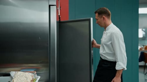 professional kitchen chef looks into the fridge and chooses ingredients for cooking food concept