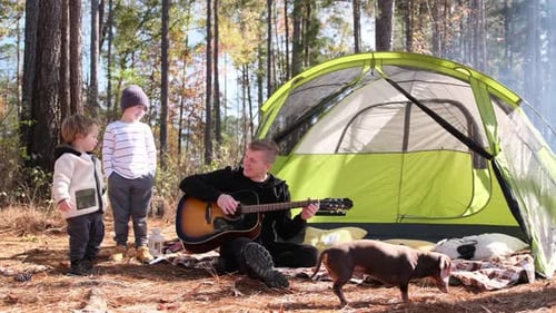 Man Plays Guitar While Camping With Family