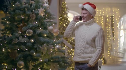 Festive Young Man Talking on Phone Near Christmas Tree