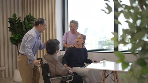Senior Friends Chatting Together Indoors Near Window