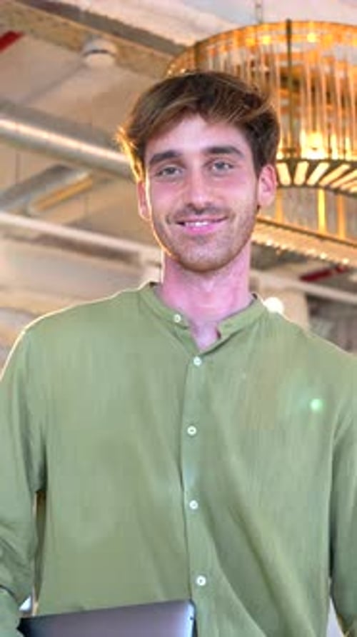 Smiling Man Holding Laptop Inside Office Space