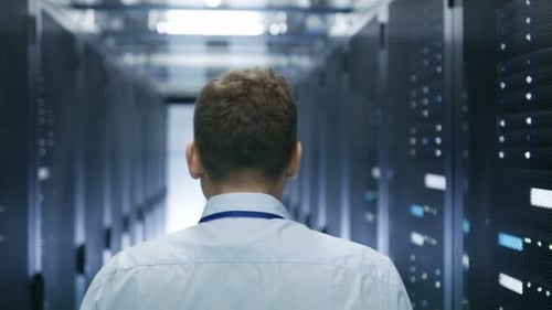Nächste Aufnahme eines IT-Technikers, der durch das Rechenzentrum geht. Reihen funktionierender Server-Racks sind sichtbar