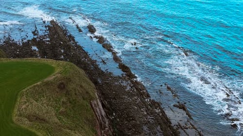 Rocky Coast with Waves Crashing Against Jagged Shoreline Ocean Surf Hitting Sharp Rocks Along Rugged