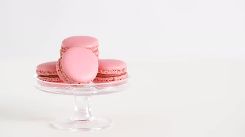 Sweets, Pastry and Food Concept - Pink Macarons on Glass Confectionery Stand