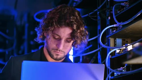 Young Adult Typing on Laptop in Server Room