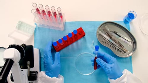 Person Removing Red Liquid Vial in Lab