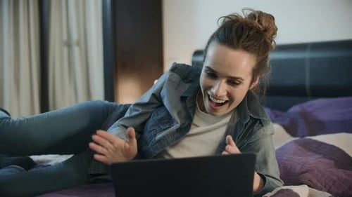 Excited Woman Lying on Bed Using Laptop