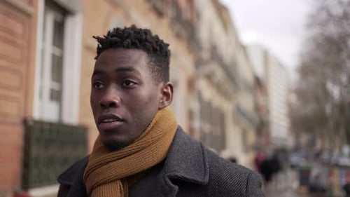Young elegant black African man walking outside in city sidewalk