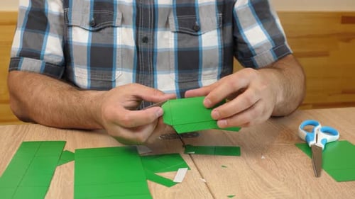 Man Creating Origami Box on Wooden Table