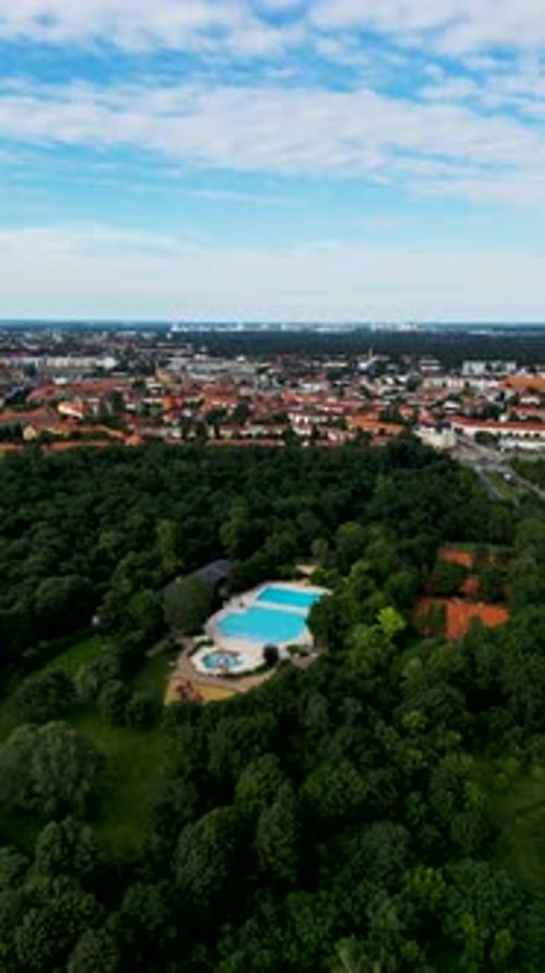 Aerial view of public pool surrounded by forest and cityscape, Berlin, Germany.