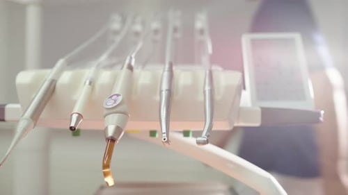 Dentist moves behind set of tools used during oral exam and treatment, close-up