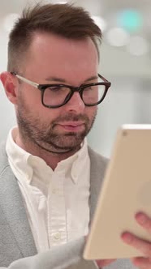 Man Wearing Glasses Using a Tablet Device