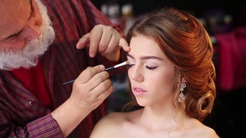 Makeup Artist Applying Eyeshadow to Beautiful Young Woman