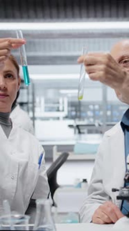 Vidéo verticale Chercheur principal enseignant à un stagiaire dans un laboratoire pour évaluer des solutions composées