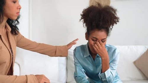 Concerned Woman Comforting a Sad Friend on Couch