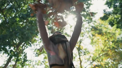 Woman, autumn and throwing leaves outdoor in a park with trees, freedom and fun in nature