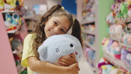In a Vibrant Toy Store a Delighted Child with an Adorable Plush Toy Spreads Joy and Innocence The