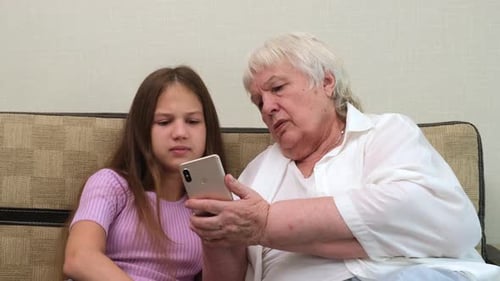 Grandmother and Girl Looking at a Cellphone Indoors