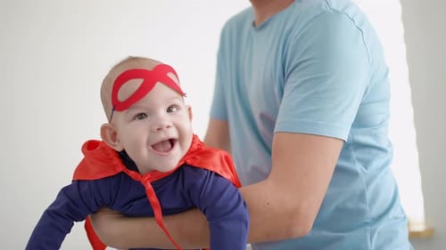 Adorable Infant Wearing Superhero Costume Held by Adult