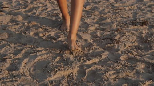 Closeup Shot Of A Person's Legs Walking Barefoot On A Sandy Beach