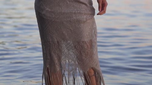 Woman in Dress Standing in Water at Sunset