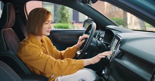 Belle jeune femme configurant la navigation sur un écran à l'intérieur d'une voiture moderne, se préparant pour un essai routier