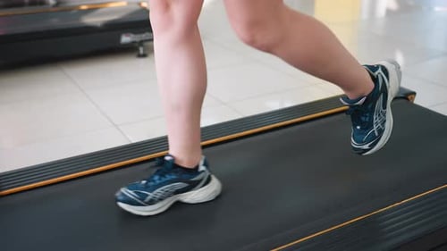 Beinlaufen mit Seitenansicht auf dem Laufband im modernen Indoor-Fitnessstudio mit Geräten in der Nähe