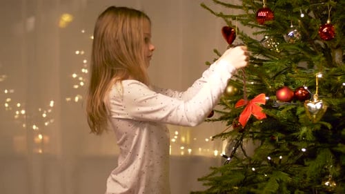 Girl decorating a festive Christmas tree with ornaments