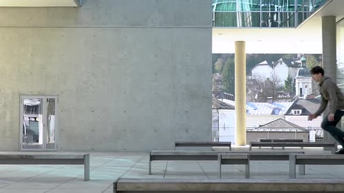 Slow motion shot of a young parkour athlete jumping from bench to bench in a urban place