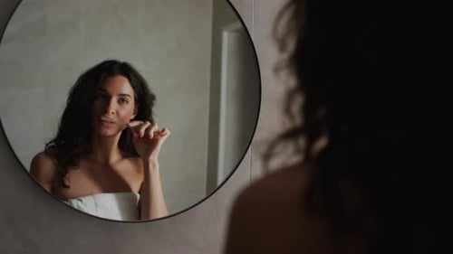 Woman Brushing Teeth in Bathroom Mirror