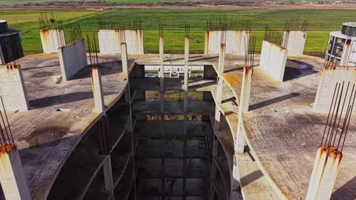 Sitio de construcción abandonado con hormigón visto y barras de refuerzo al atardecer