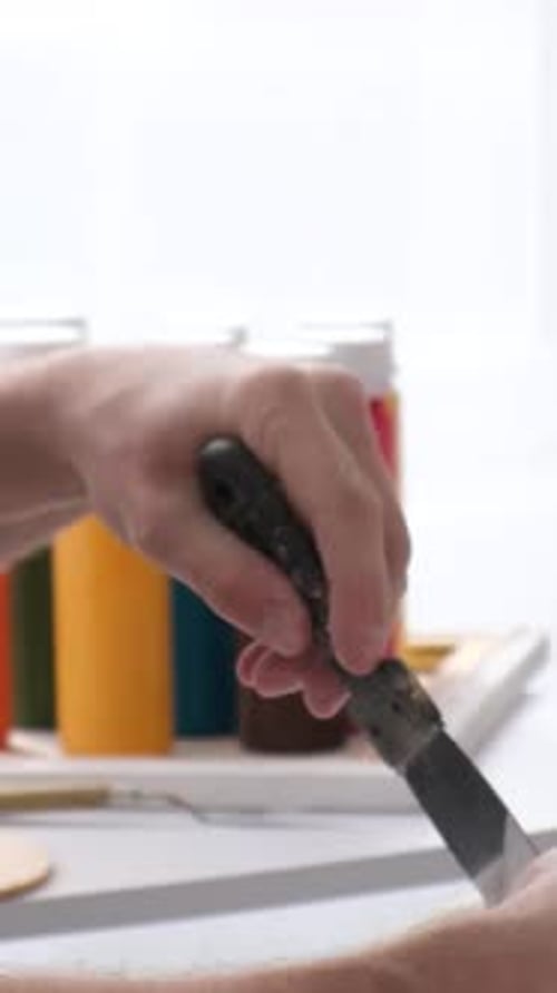 De cerca La mano del pintor agita la pintura blanca del recipiente con una espátula Vídeo vertical