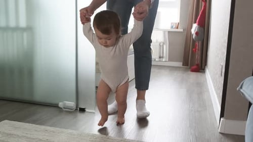 Infant Barefoot Baby Girl Learning to Walk Standing on Warm Carpet