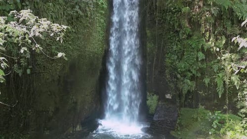 Drone View of Narrow Stream Plunging Down Mossy Tropical Jungle Waterfall in Ubud Bali