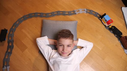 Boy Lying Down as Toy Train Passes By