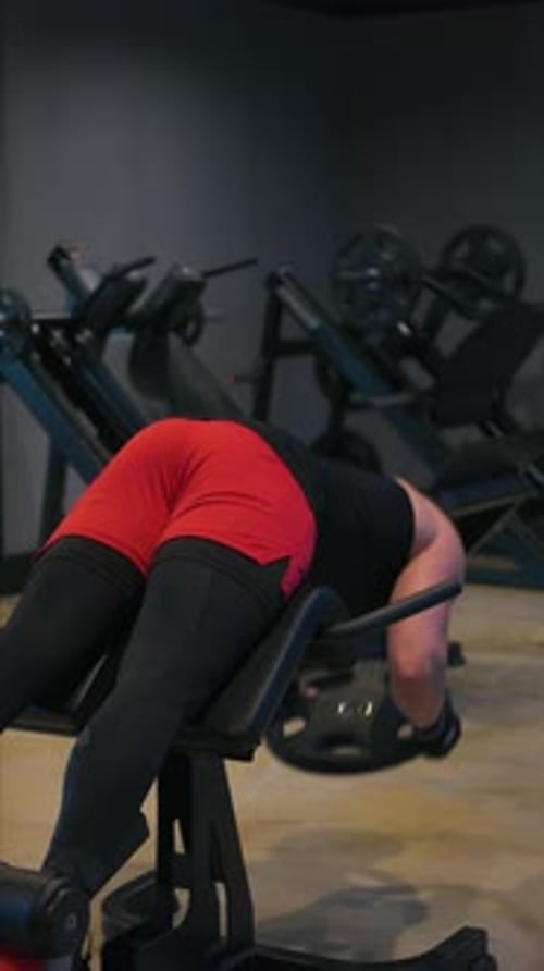 Man Doing Weighted Back Extension Exercise in Gym